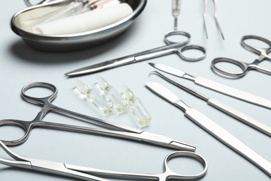 Photo of Different surgical instruments on light grey background, closeup