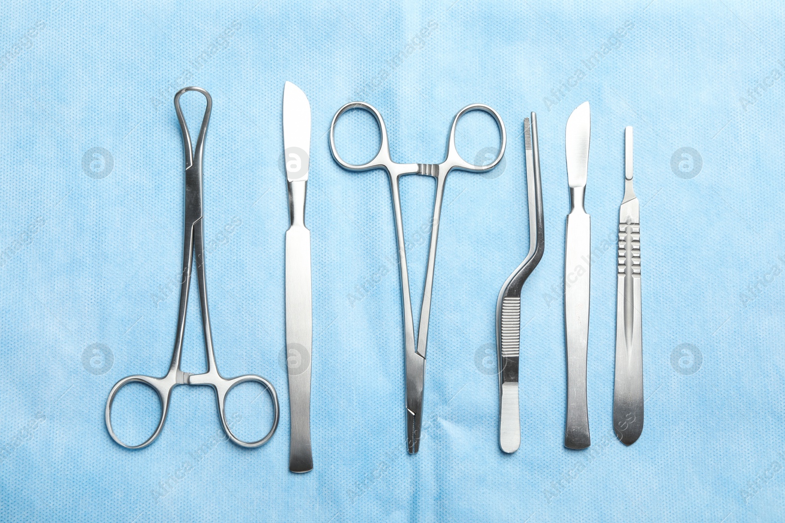 Photo of Different surgical instruments on light blue gauze, flat lay