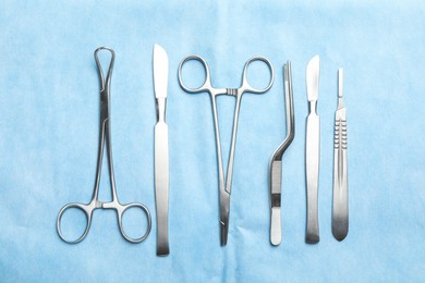 Different surgical instruments on light blue gauze, flat lay