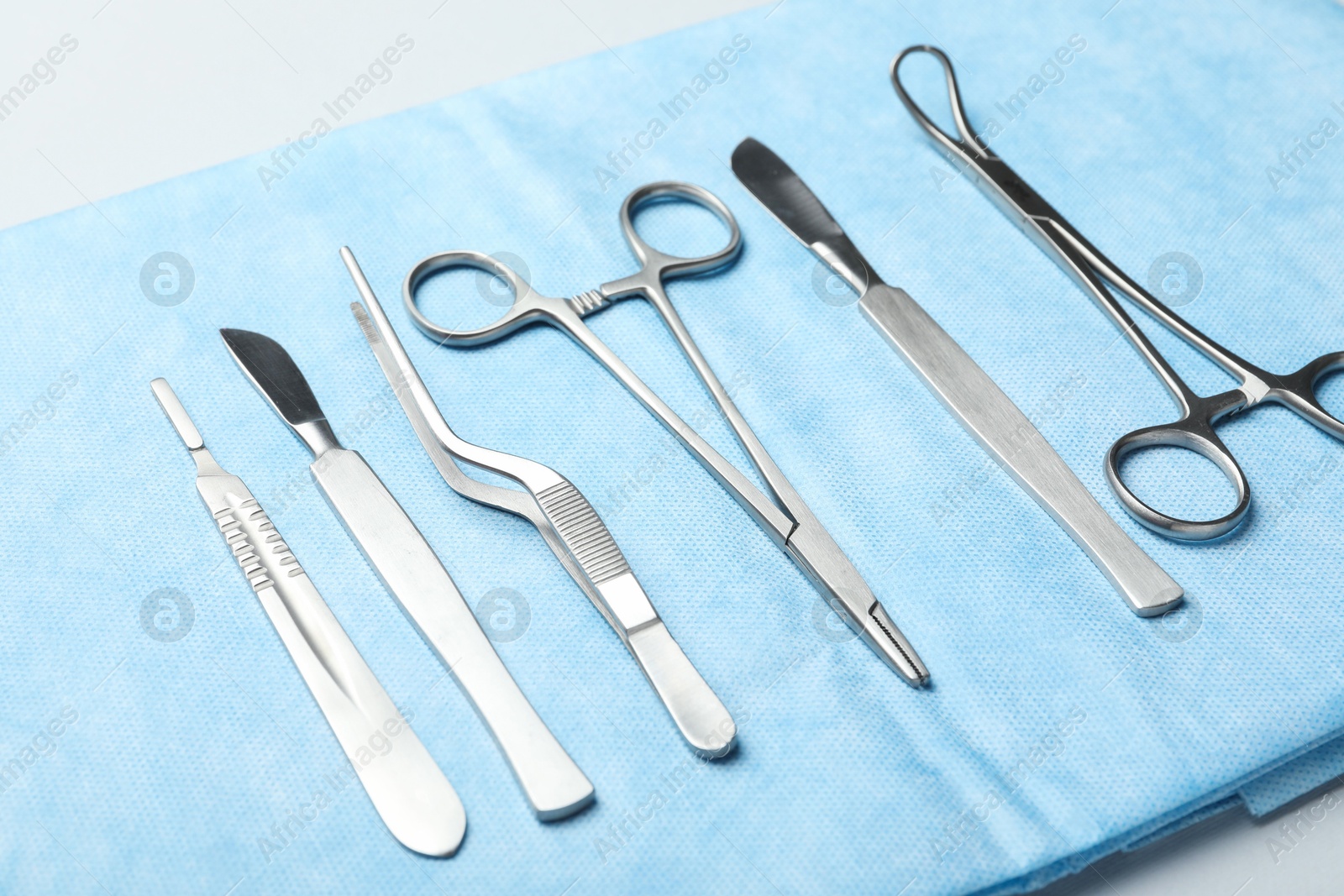 Photo of Different surgical instruments and light blue gauze on white table, closeup