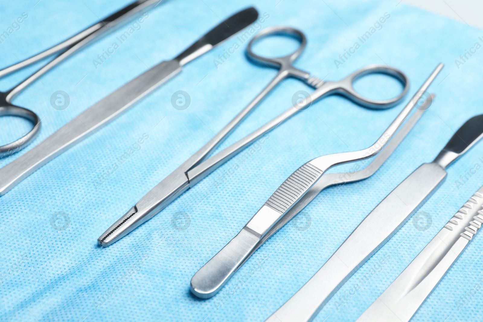 Photo of Different surgical instruments on light blue gauze, closeup