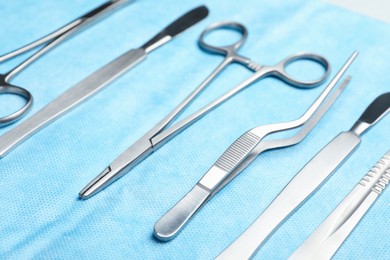 Photo of Different surgical instruments on light blue gauze, closeup