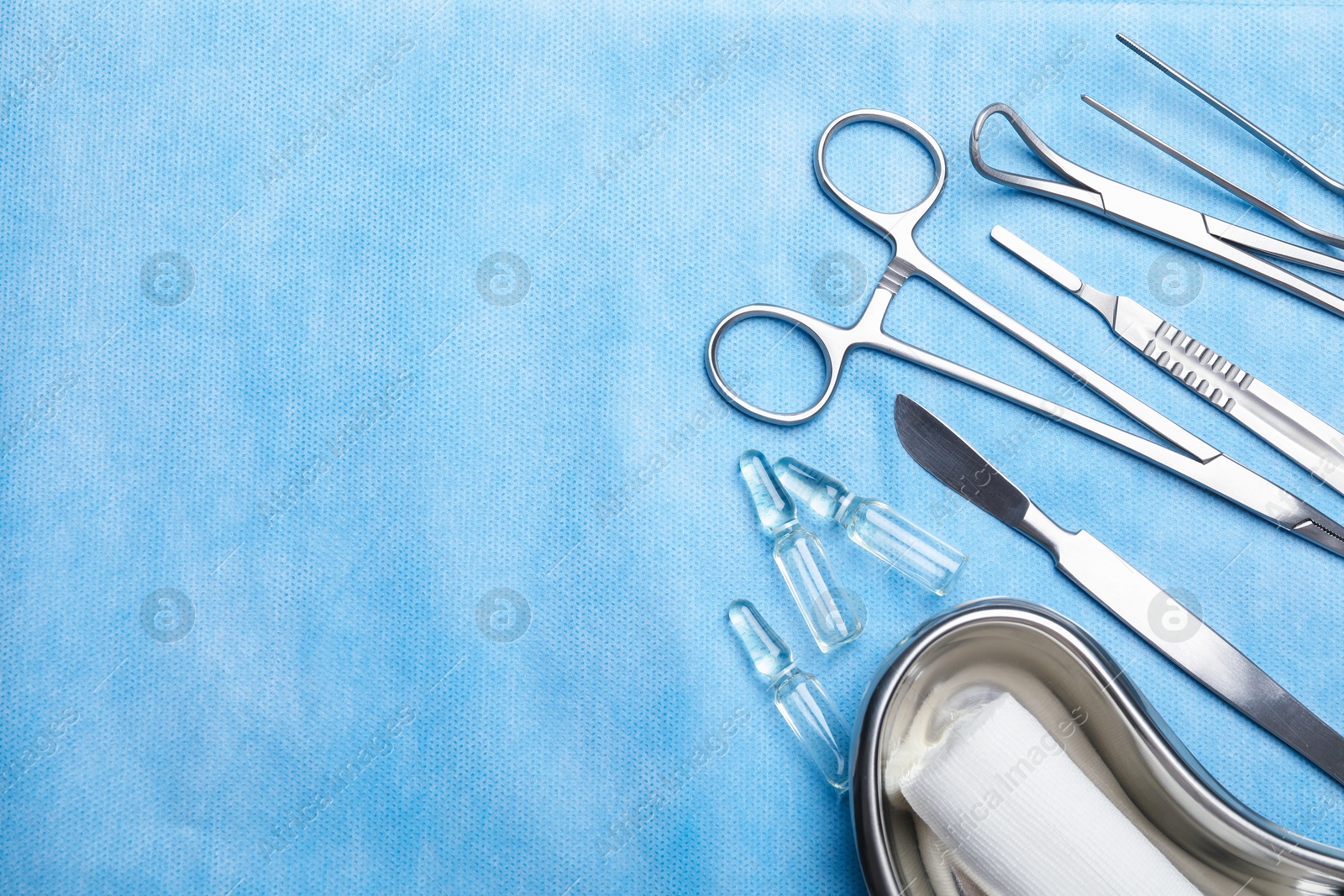 Photo of Different surgical instruments on light blue gauze, flat lay. Space for text