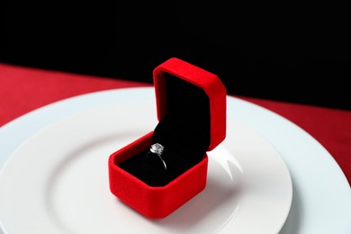 Beautiful engagement ring and setting for romantic dinner on red table, closeup