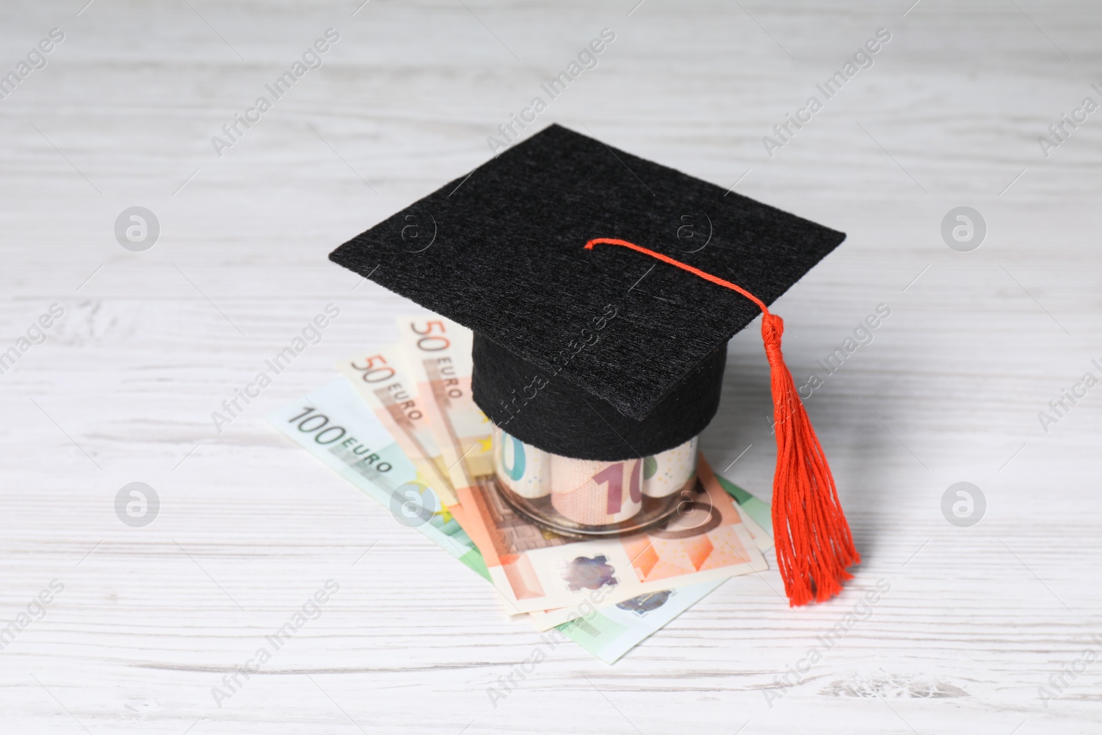 Photo of Graduate hat and euro banknotes on light wooden table. Tuition payment