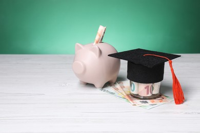 Photo of Graduate hat, euro banknotes and piggy bank on light wooden table, space for text. Tuition payment