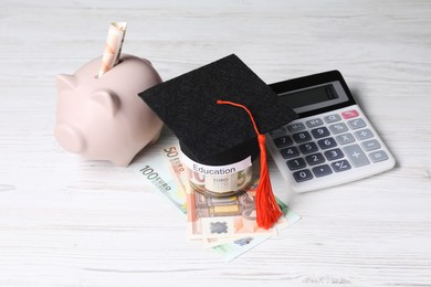 Photo of Graduate hat, euro banknotes, piggy bank, calculator and glass jar with word Education on light wooden table. Tuition payment