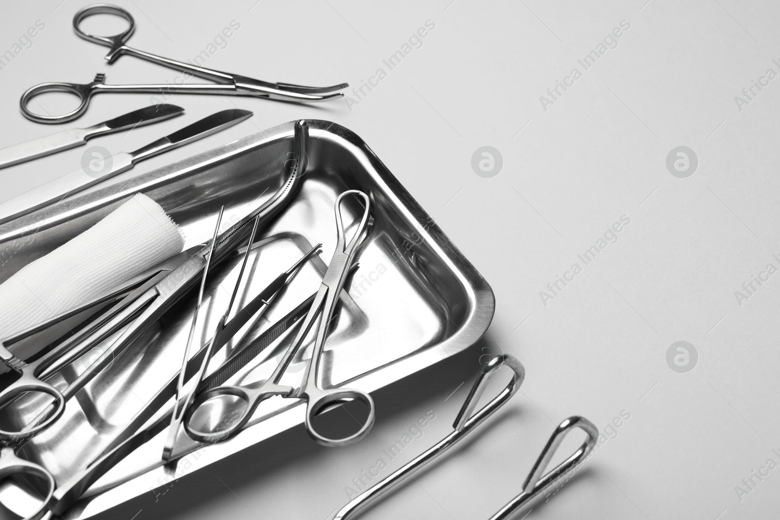 Photo of Different surgical tools on light gray background, closeup. Space for text