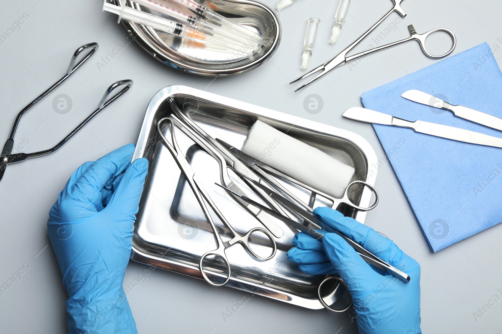 Photo of Doctor with different surgical tools on gray background, top view