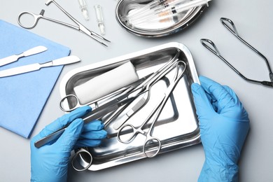 Doctor with different surgical tools on gray background, top view