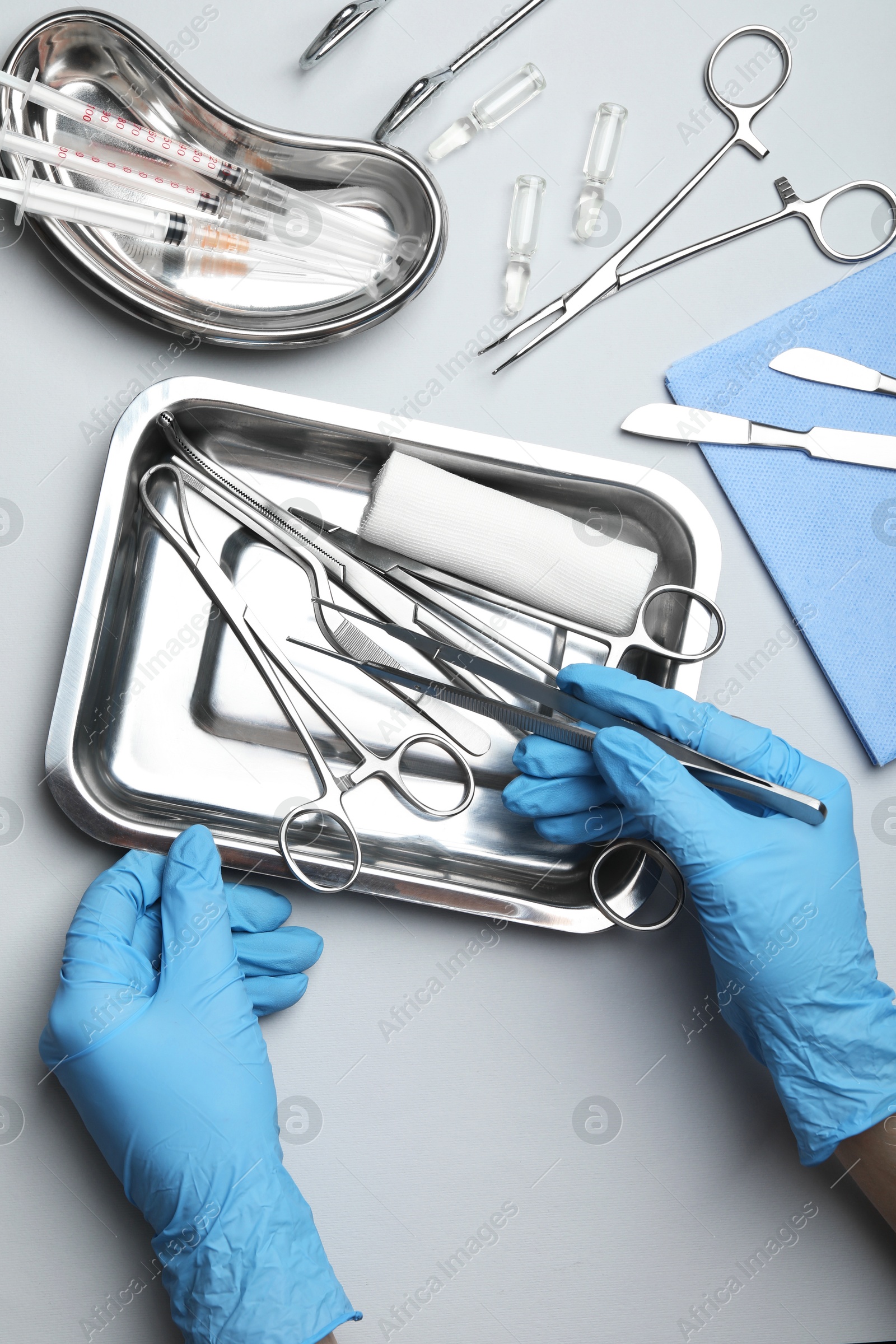 Photo of Doctor with different surgical tools on gray background, top view