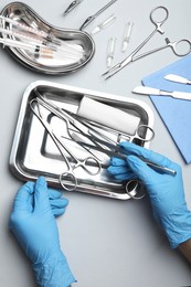 Doctor with different surgical tools on gray background, top view