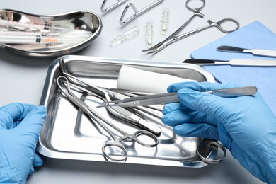 Photo of Doctor with different surgical tools on gray background, closeup