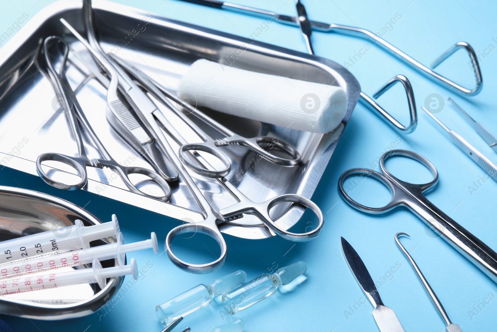 Photo of Different surgical tools on light blue background, closeup