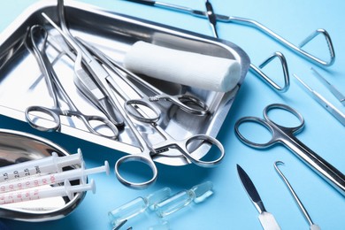 Photo of Different surgical tools on light blue background, closeup