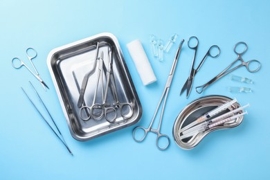 Different surgical tools on light blue background, flat lay