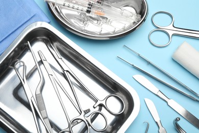 Different surgical tools on light blue background, flat lay