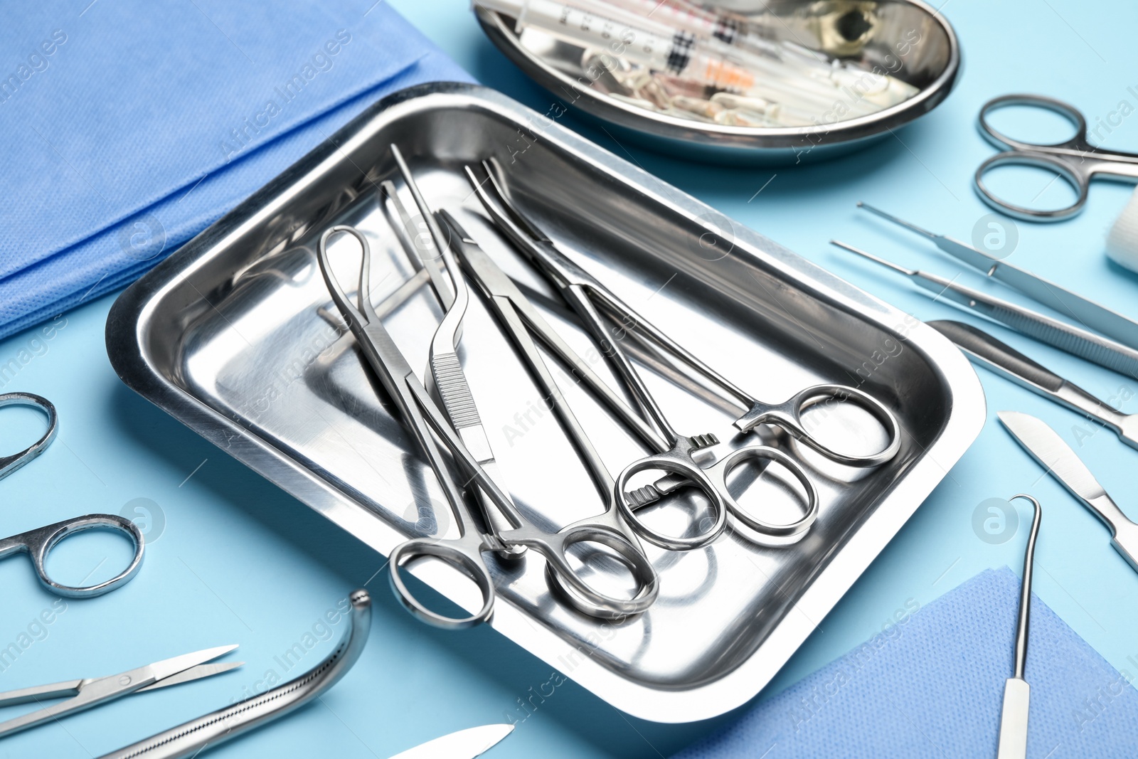 Photo of Different surgical tools on light blue background, closeup