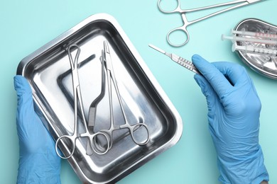 Photo of Doctor with different surgical tools on turquoise background, top view