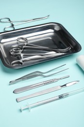 Photo of Different surgical tools on turquoise background, closeup