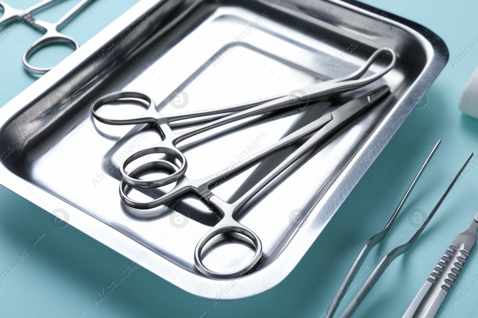 Photo of Different surgical tools on turquoise background, closeup