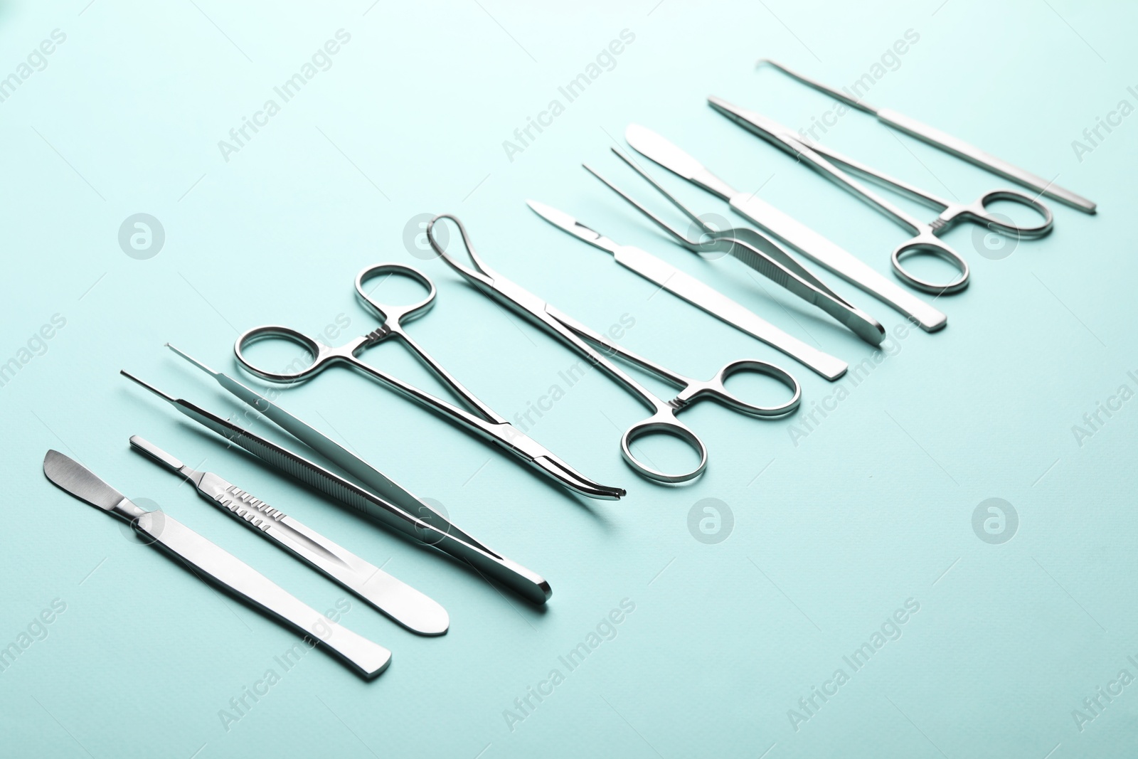 Photo of Different surgical tools on turquoise background, closeup