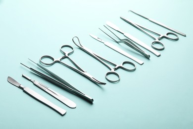 Photo of Different surgical tools on turquoise background, closeup