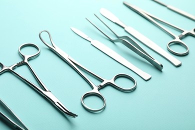 Photo of Different surgical tools on turquoise background, closeup