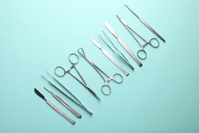 Photo of Different surgical tools on turquoise background, flat lay