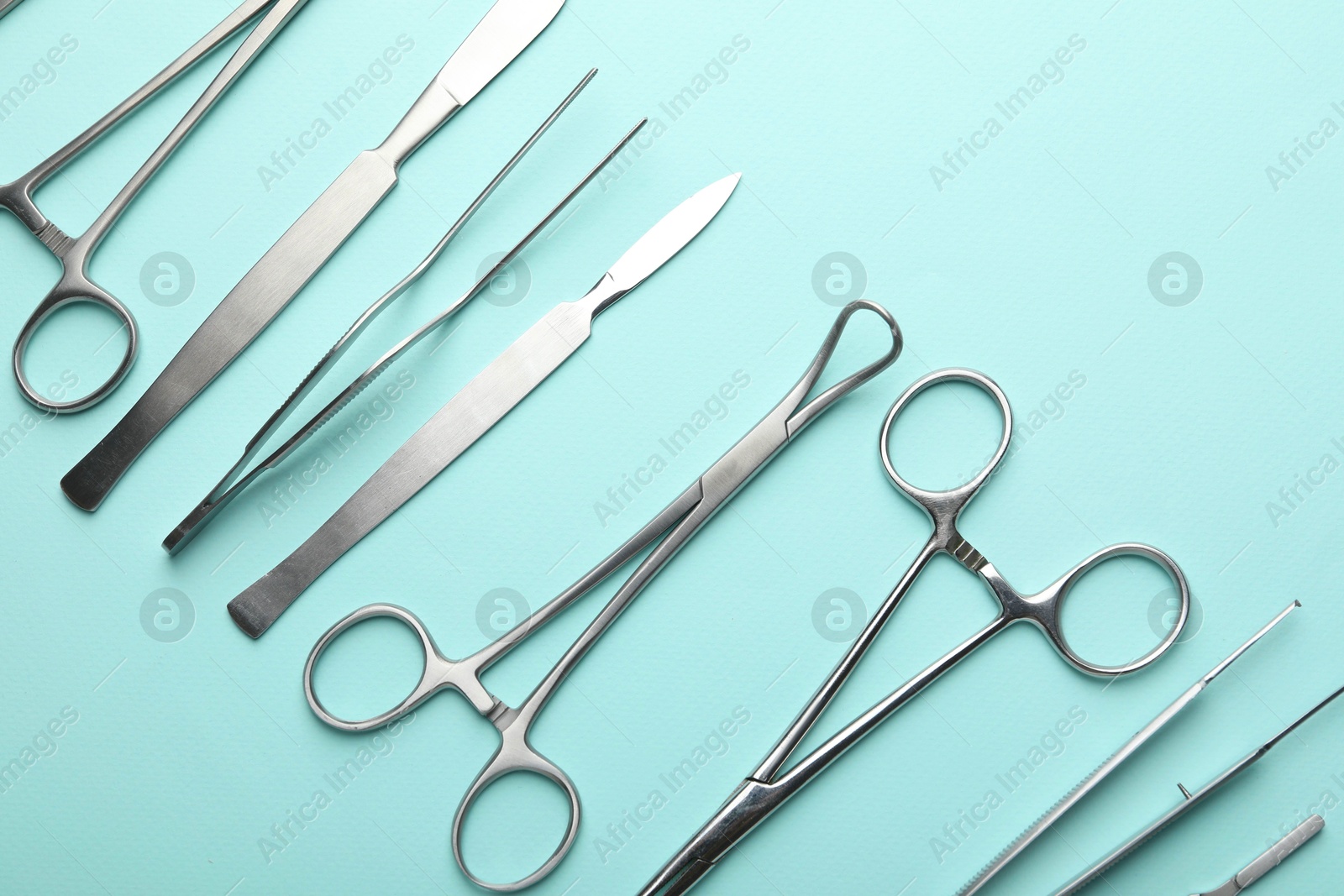 Photo of Different surgical tools on turquoise background, flat lay