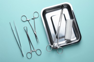 Different surgical tools on turquoise background, flat lay