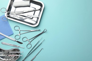 Photo of Different surgical tools on turquoise background, flat lay. Space for text