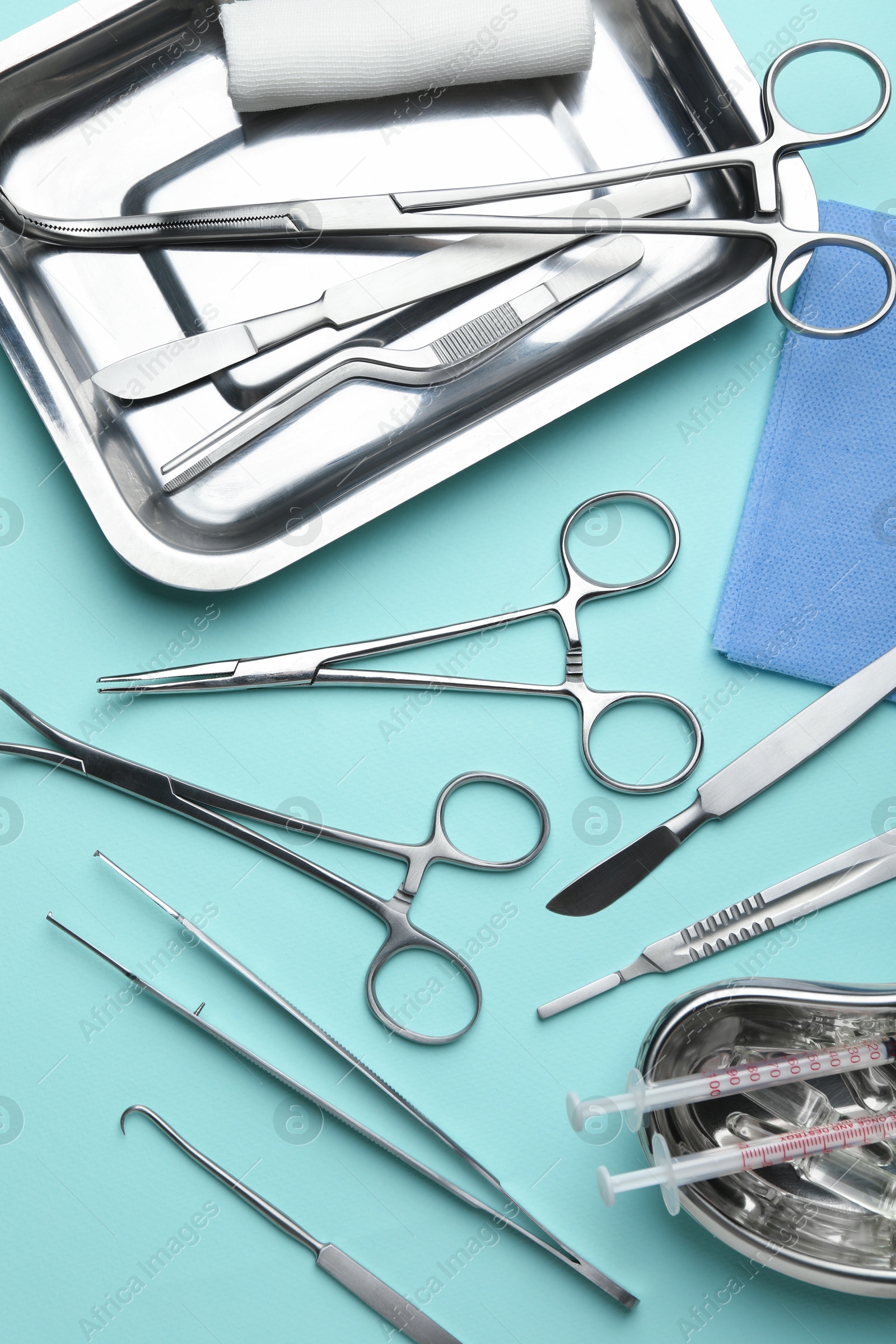 Photo of Different surgical tools on turquoise background, flat lay