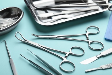 Photo of Different surgical tools on turquoise background, closeup