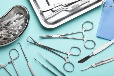 Different surgical tools on turquoise background, flat lay