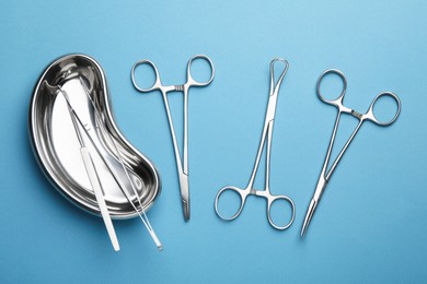 Different surgical tools on light blue background, flat lay