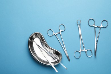 Different surgical tools on light blue background, flat lay. Space for text