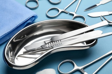 Photo of Different surgical tools on light blue background, closeup