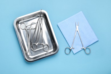 Different surgical tools on light blue background, flat lay