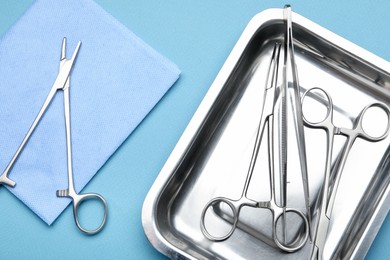 Photo of Different surgical tools on light blue background, flat lay