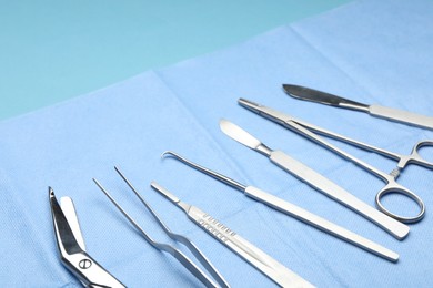 Photo of Different surgical tools on light blue background, closeup