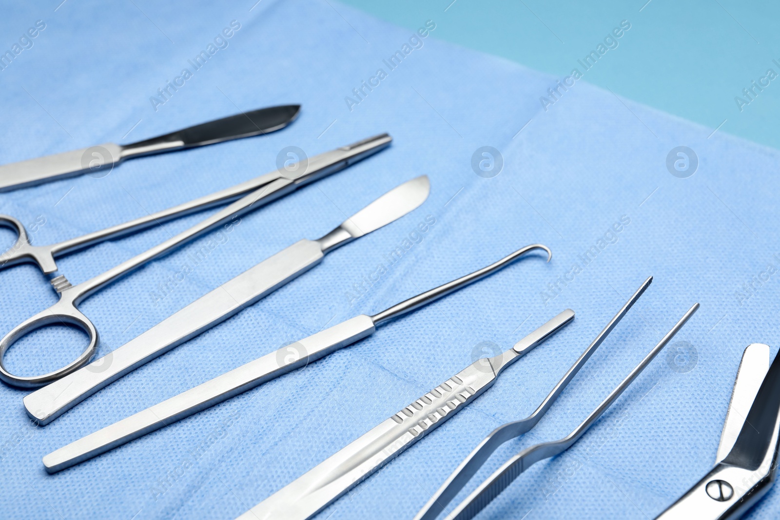 Photo of Different surgical tools on light blue background, closeup