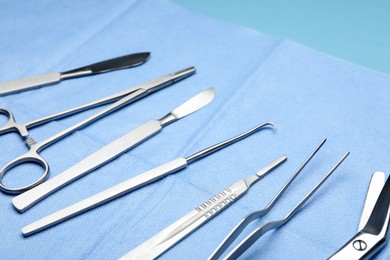 Photo of Different surgical tools on light blue background, closeup