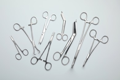 Photo of Different surgical tools on light gray background, flat lay