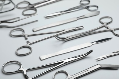 Photo of Different surgical tools on light gray background, closeup