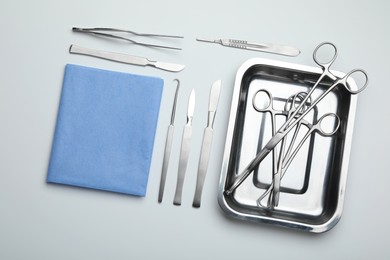 Photo of Different surgical tools on light gray background, flat lay