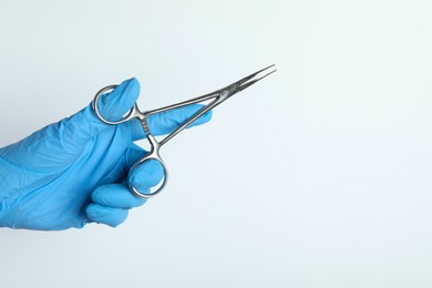 Photo of Doctor with surgical forceps on white background, closeup. Space for text