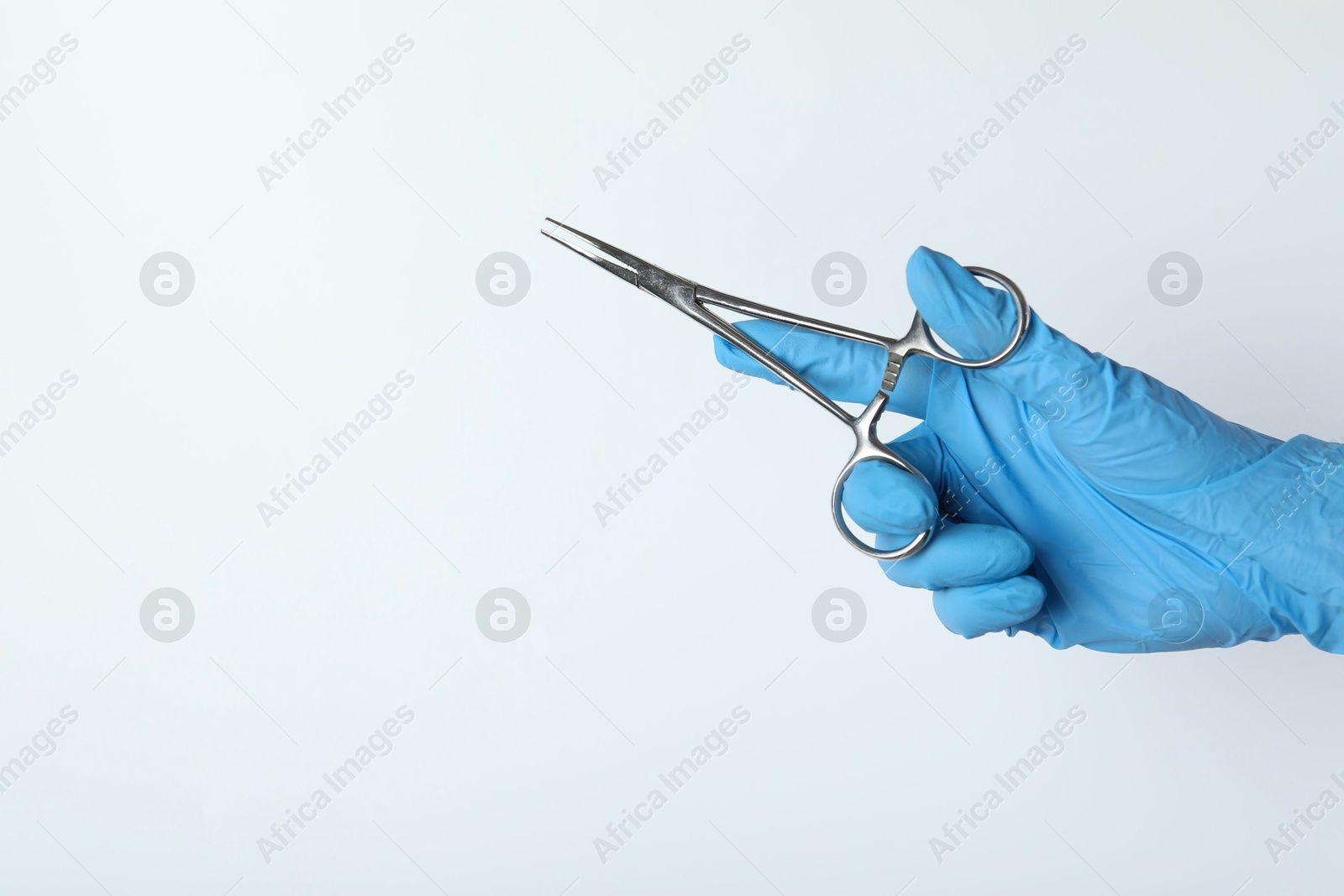 Photo of Doctor with surgical forceps on white background, closeup. Space for text