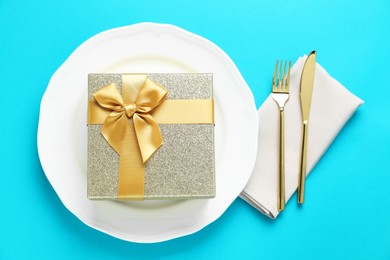 Beautiful table setting with romantic gift on light blue background, flat lay