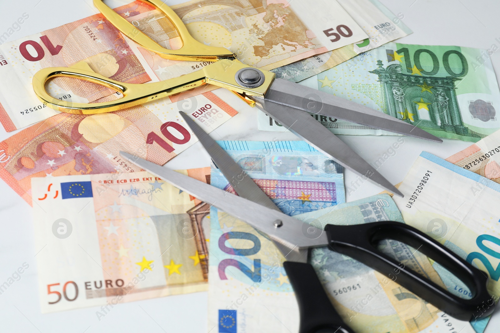 Photo of Euro banknotes and scissors on light table, closeup